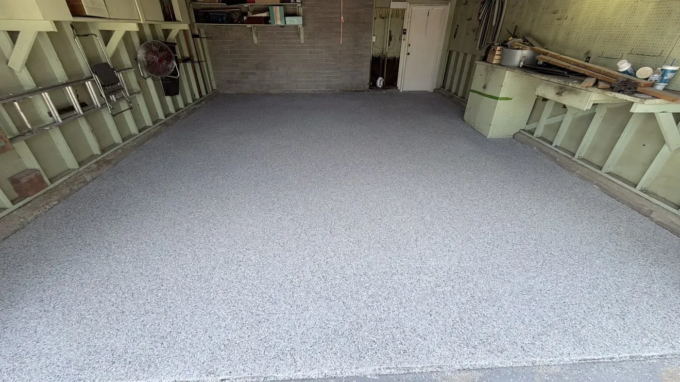 Garage floor in the Olympic flake blend, with a workbench and shelving along the walls