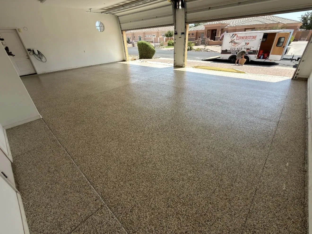 Garage floor in the Chestnut flake blend, with the Cornerstone Coatings trailer parked in the driveway